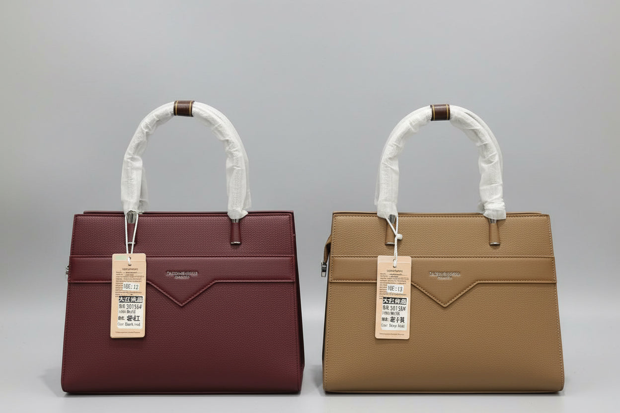 Two structured handbags displayed side by side on a shelf. The left bag is a deep burgundy red, and the right bag is a warm tan brown.